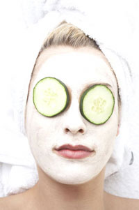 A woman with cucumbers over her eyes and a face mask